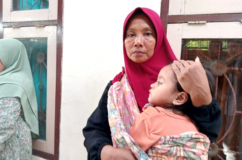 Ibu buta huruf Sulimah tengah menggendong anaknya.